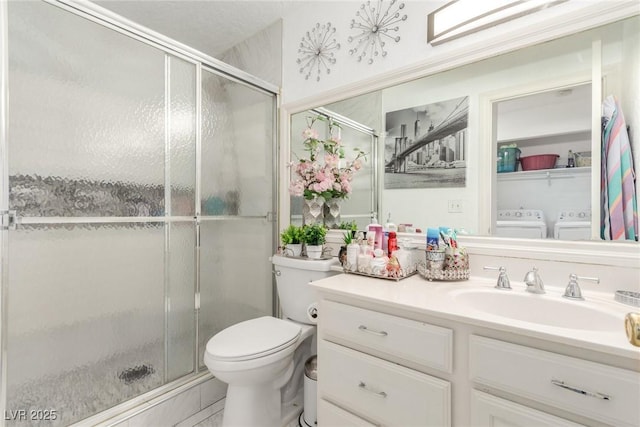 bathroom featuring walk in shower, independent washer and dryer, vanity, and toilet