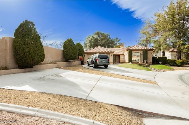 view of front of home with a garage, a tiled roof, driveway, stucco siding, and a chimney