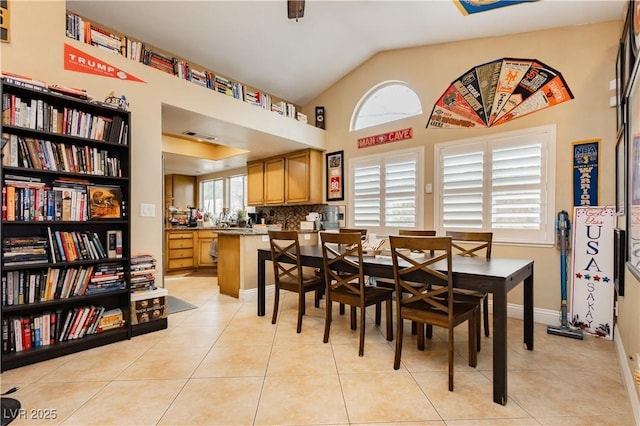 dining area with vaulted ceiling, light tile patterned floors, and baseboards