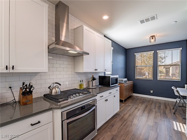 kitchen with wall chimney exhaust hood, stainless steel appliances, and white cabinets