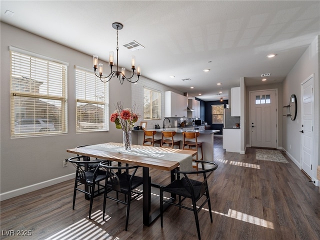 dining space featuring dark wood-type flooring, sink, and an inviting chandelier