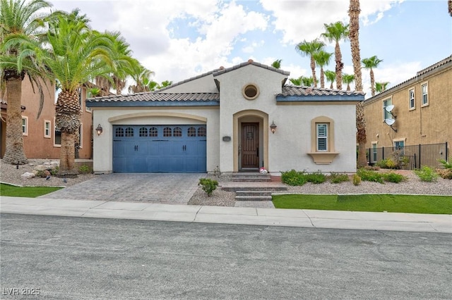 mediterranean / spanish-style house with stucco siding, a tile roof, decorative driveway, and a garage