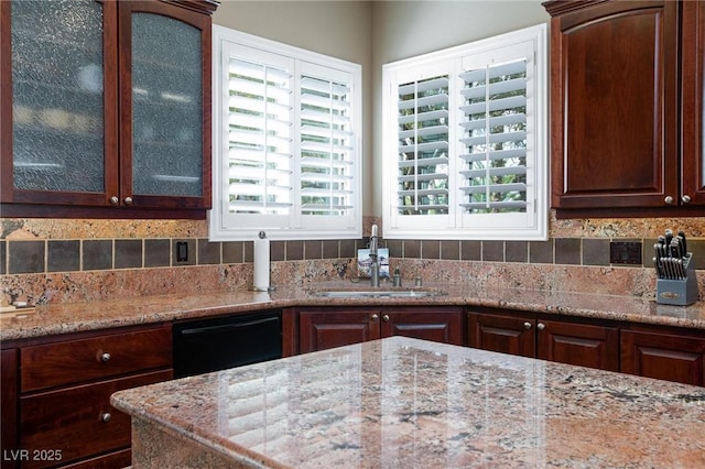 kitchen with dark brown cabinetry, black dishwasher, sink, and light stone counters