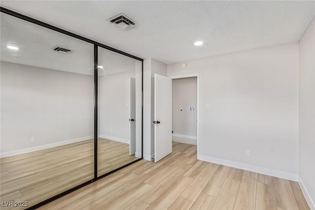 unfurnished bedroom with a closet and light wood-type flooring