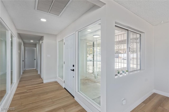 doorway to outside with a textured ceiling and light wood-type flooring