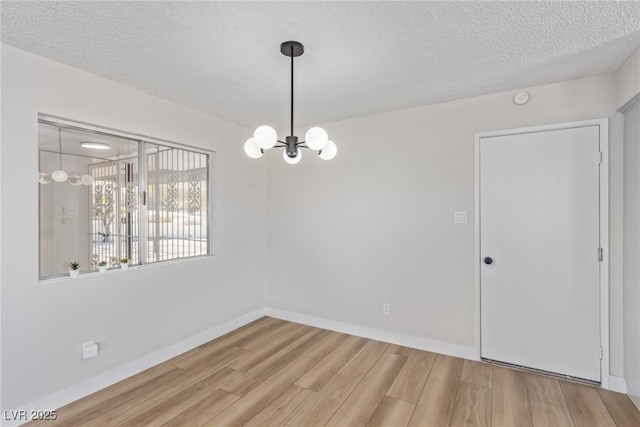 unfurnished room featuring hardwood / wood-style floors, a textured ceiling, and an inviting chandelier