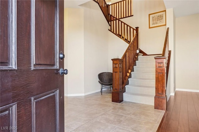 foyer entrance featuring stairway, light tile patterned floors, and baseboards