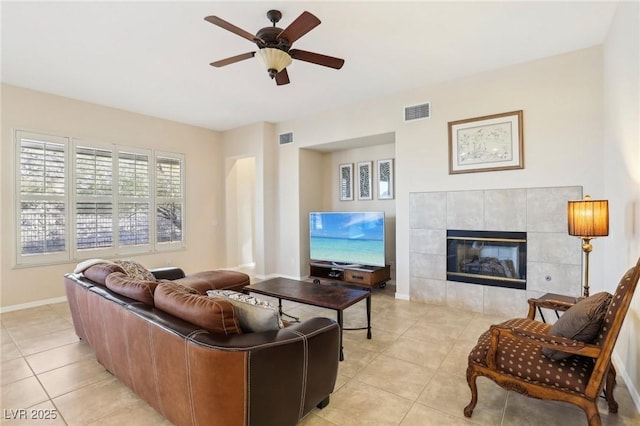 living room with light tile patterned flooring, ceiling fan, and a fireplace