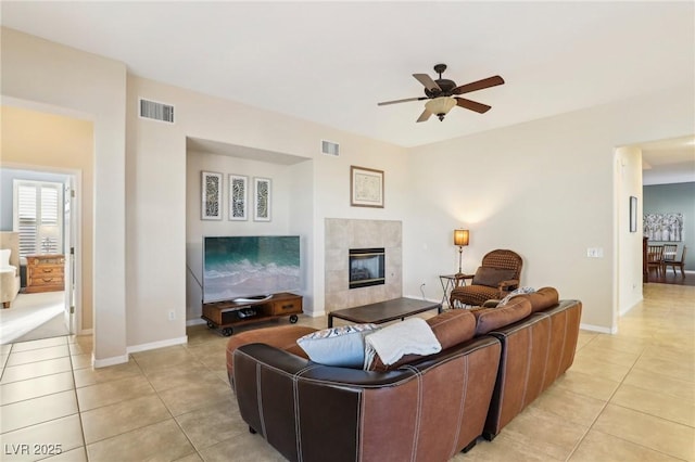 tiled living room with ceiling fan and a tiled fireplace