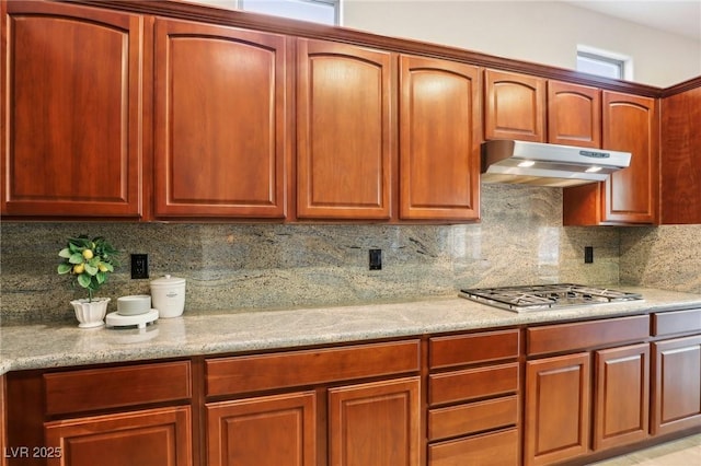 kitchen featuring stainless steel gas stovetop, light stone countertops, and decorative backsplash