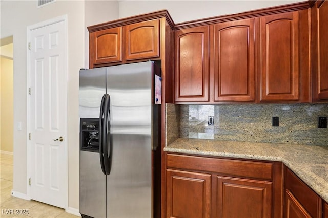 kitchen featuring light stone counters, stainless steel fridge with ice dispenser, light tile patterned floors, and backsplash