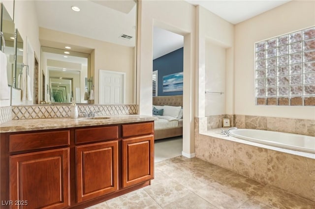 bathroom featuring tasteful backsplash, vanity, and tiled tub