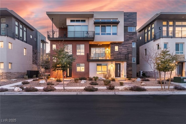 contemporary home with stone siding, central AC, and stucco siding