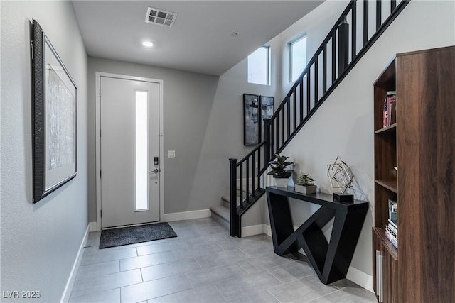 entryway with stairway, baseboards, light tile patterned floors, and visible vents