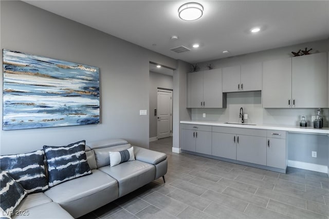 kitchen with gray cabinets, light countertops, visible vents, open floor plan, and a sink