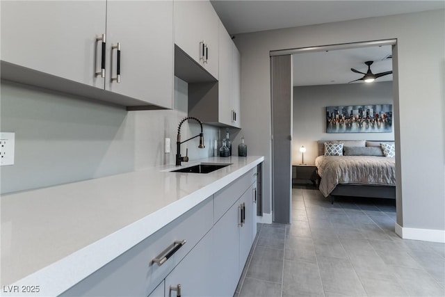 kitchen featuring light countertops, a ceiling fan, open floor plan, white cabinets, and a sink