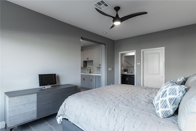 bedroom with ceiling fan, connected bathroom, sink, and dark tile patterned floors