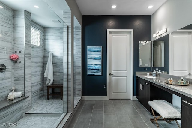 bathroom with a tile shower and vanity