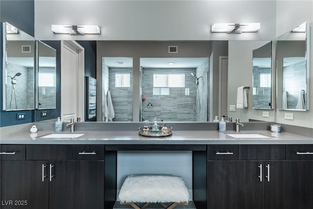 full bathroom with a healthy amount of sunlight, a tile shower, and a sink