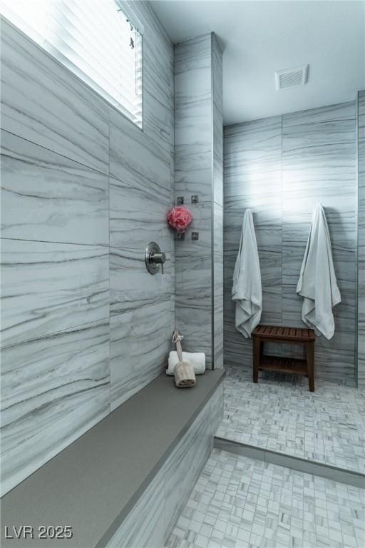 full bathroom with visible vents, tile walls, and tiled shower