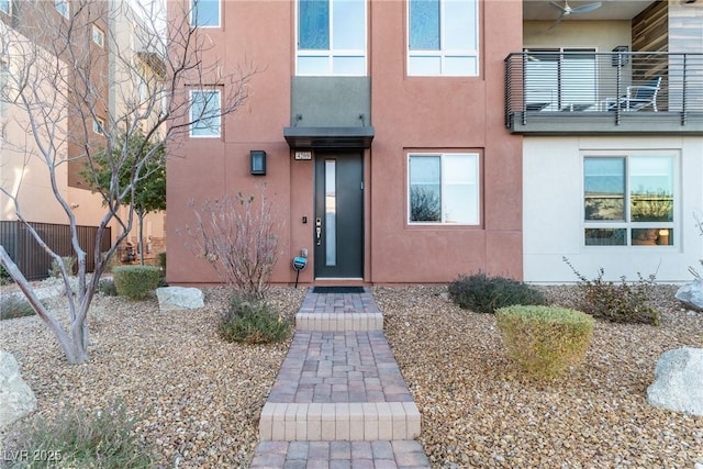 doorway to property with elevator, a balcony, and stucco siding