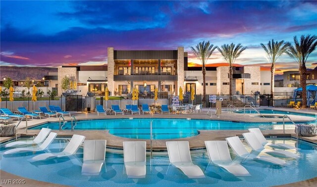 pool at dusk with a community hot tub and a patio area