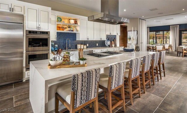 kitchen with island range hood, tasteful backsplash, white cabinetry, a kitchen bar, and stainless steel appliances