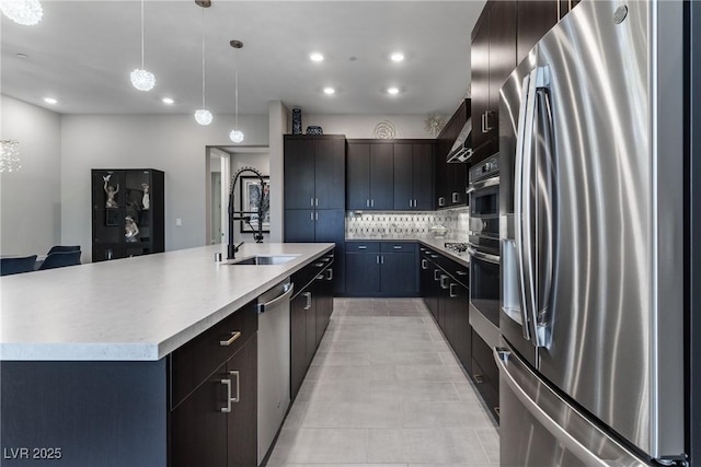 kitchen with decorative backsplash, appliances with stainless steel finishes, hanging light fixtures, light countertops, and a sink