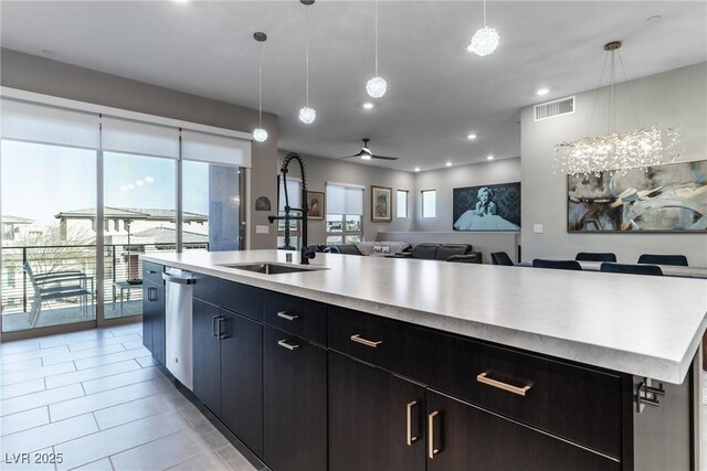 kitchen with a kitchen island with sink, sink, decorative light fixtures, and dishwasher