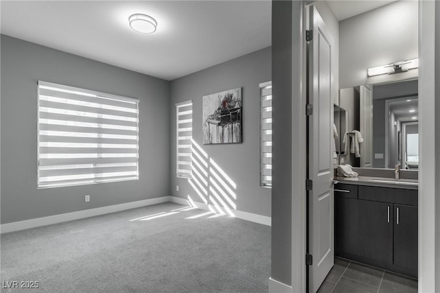 spare room with carpet floors, a sink, and baseboards