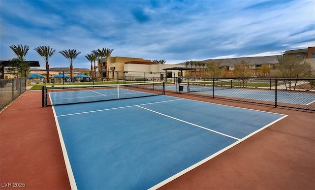 view of tennis court with a residential view and fence