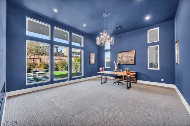 office space with an inviting chandelier, a towering ceiling, and carpet