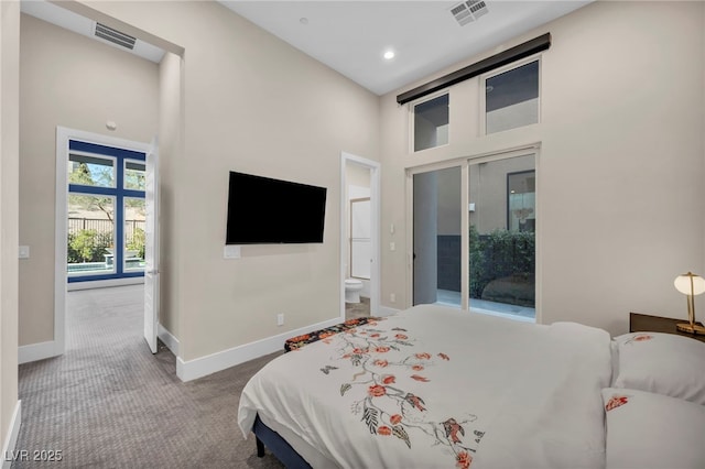 bedroom with a towering ceiling, ensuite bathroom, and carpet