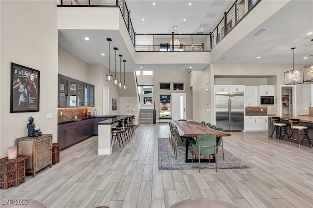 dining space featuring an inviting chandelier, light hardwood / wood-style floors, and a high ceiling