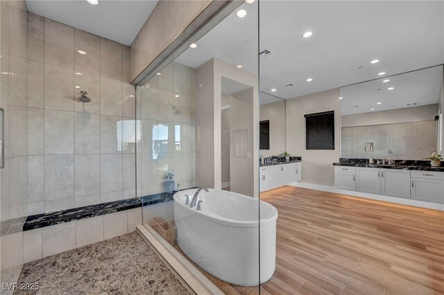 bathroom featuring vanity, wood-type flooring, and plus walk in shower