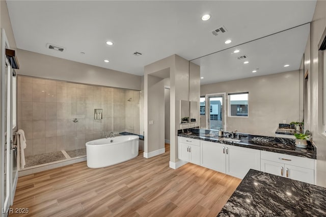 bathroom with vanity, hardwood / wood-style floors, and plus walk in shower