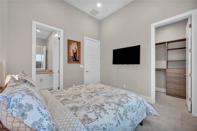 carpeted bedroom featuring a spacious closet, ensuite bath, and a closet