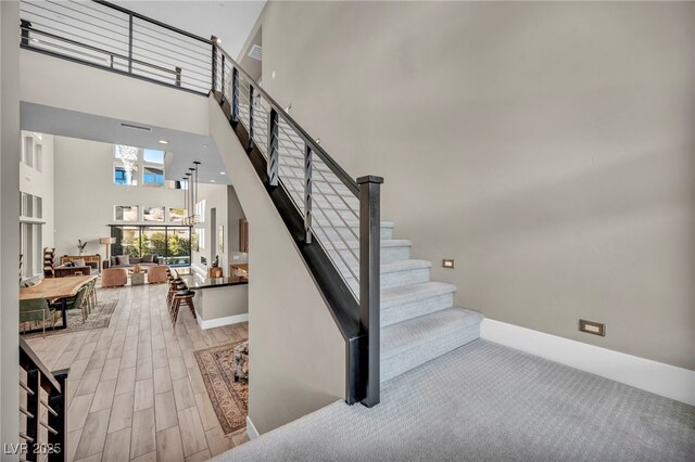 stairway featuring a towering ceiling and wood-type flooring