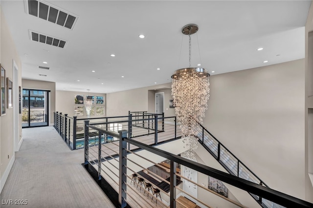 corridor with light carpet and a notable chandelier