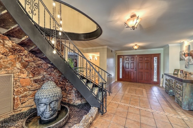 entrance foyer with visible vents, baseboards, ornamental molding, stairway, and tile patterned floors