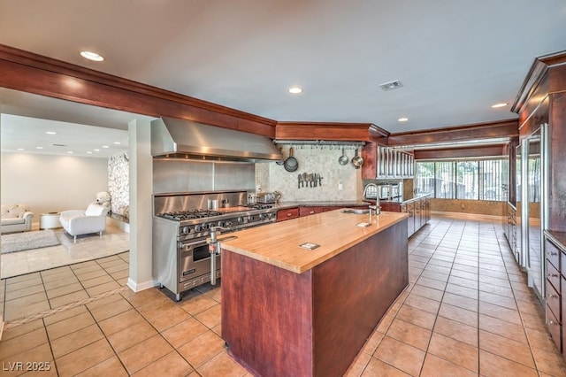 kitchen with light tile patterned floors, visible vents, range hood, luxury range, and wooden counters