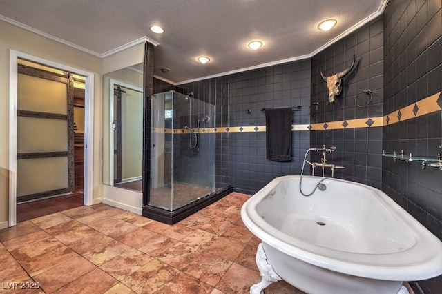 full bath with a textured ceiling, tile walls, a freestanding bath, ornamental molding, and a shower stall