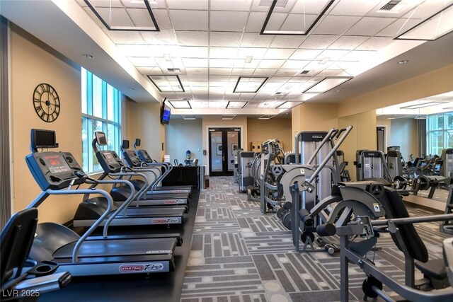 exercise room with a paneled ceiling and carpet