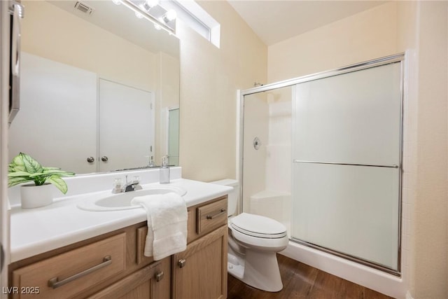 bathroom featuring vanity, hardwood / wood-style flooring, a shower with door, and toilet