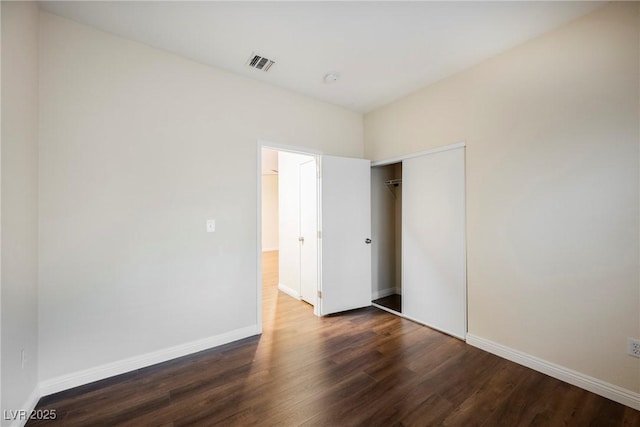 unfurnished bedroom with dark hardwood / wood-style floors and a closet