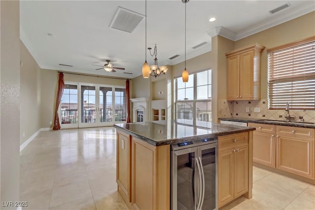 kitchen featuring a kitchen island, decorative light fixtures, sink, beverage cooler, and light brown cabinets