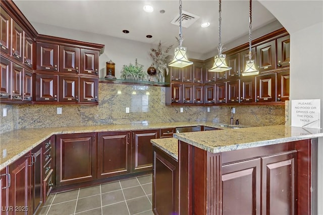 kitchen with sink, hanging light fixtures, light stone counters, tasteful backsplash, and dark tile patterned flooring