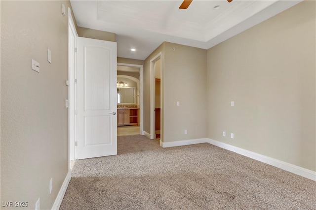 carpeted spare room featuring ceiling fan and a tray ceiling