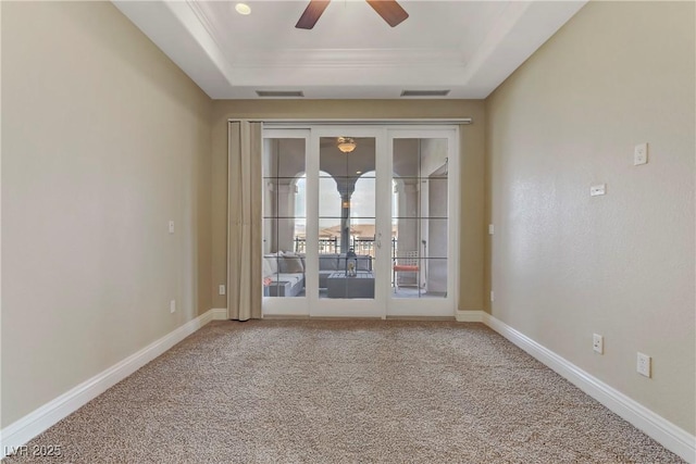 carpeted empty room with crown molding, a tray ceiling, and ceiling fan