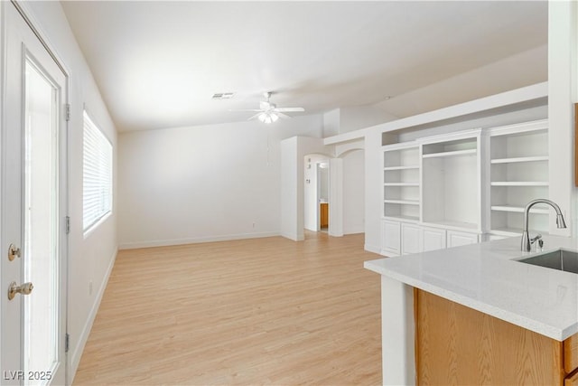 4507 Golden Palomino Ln, North Las Vegas, NV 89032 - kitchen with light wood-type flooring, a sink, a ceiling fan, vaulted ceiling, and baseboards